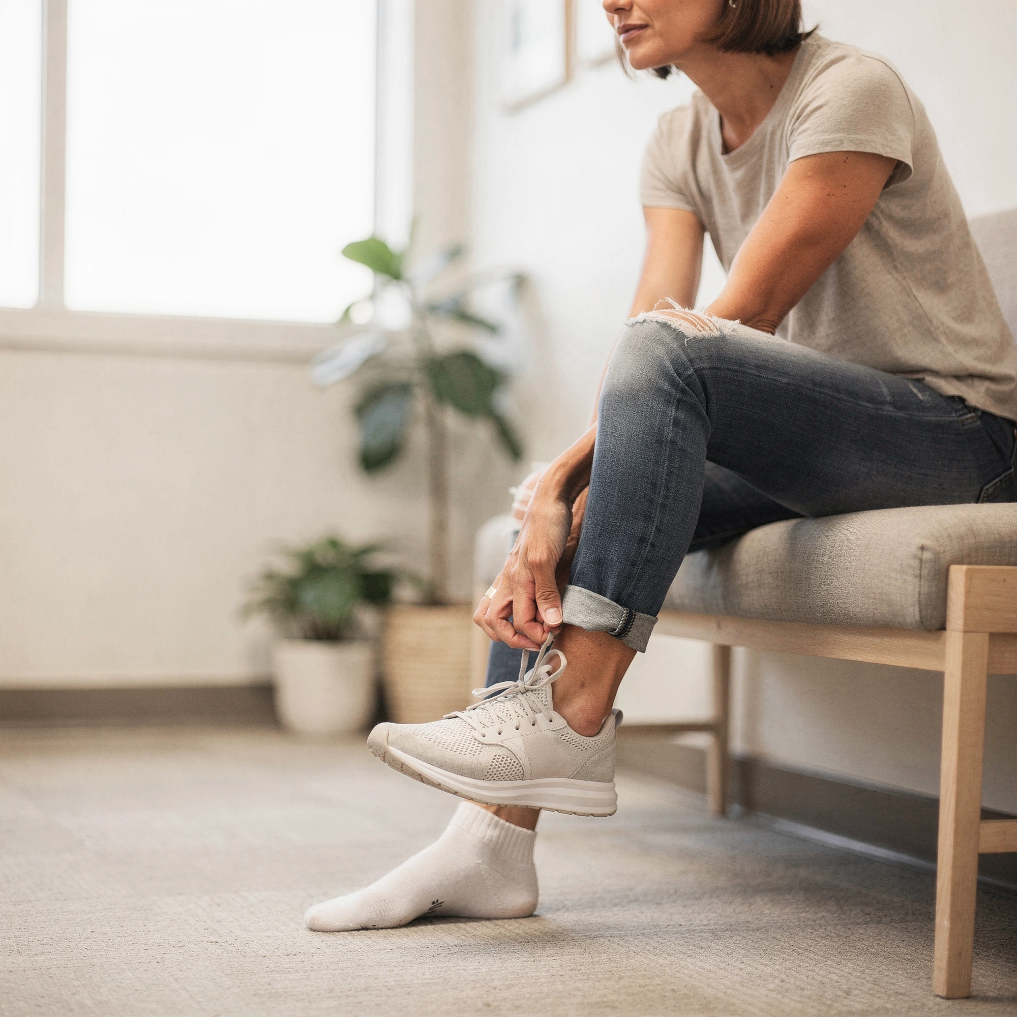 Patient seated on a bench putting on a sneaker – podiatry care in Albany, OR